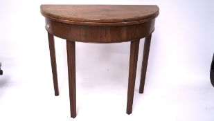 A Georgian mahogany folding table, of circular form, raised on tapered supports,