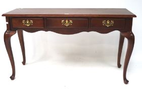 A contemporary hall table with three short drawers, raised on cabriole supports,