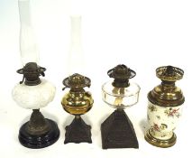 Four early 20th century oil lamps, two having glass reservoirs, the other two brass,