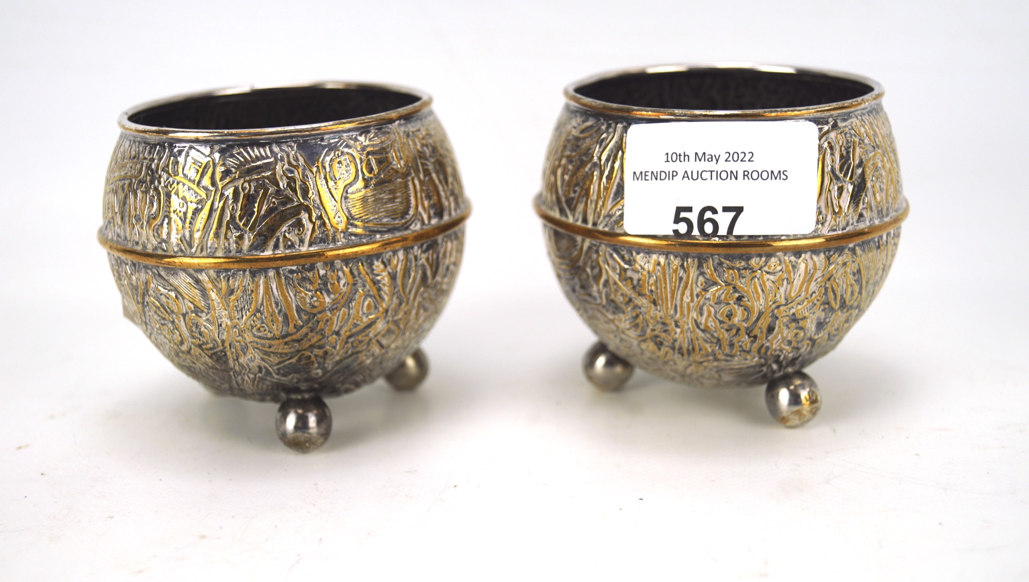 A pair of Indian white metal pots, with highly detailed hammered and embossed decoration throughout,