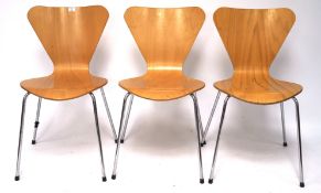 A set of three kitchen chairs, the shaped wooden frames mounted on chrome supports,