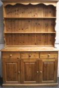 A contemporary pine kitchen dresser, the upper section with two plate racks,