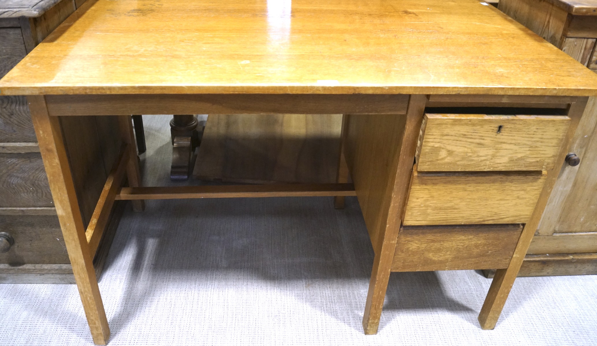 A 1960s golden oak single pedestal writing desk, two drawers to the right,