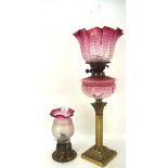 Two Victorian oil lamps, one with a brass column and base, both with fluted pink glass shades,