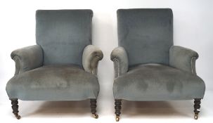 Two 20th century armchairs, upholstered in blue velvet, raised on turned supports with castors,