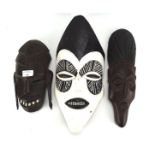 Three wooden tribal masks, one painted in black and white,