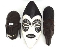 Three wooden tribal masks, one painted in black and white,