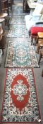 Seven small carpets/rugs, of varying designs and colours,