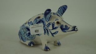 A 20th century Dutch Delft blue and white figure of a pig, in a seated position,
