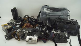 An assortment of cameras and related accessories, including a digital Pentax K110 with 18-55mm lens,