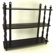An early 20th century ebonised three tier hanging wall shelf with turned supports and finials,