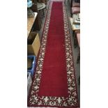 A Tabriz runner, with a cream border on a red ground, tassels to either end,