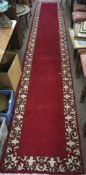 A Tabriz runner, with a cream border on a red ground, tassels to either end,