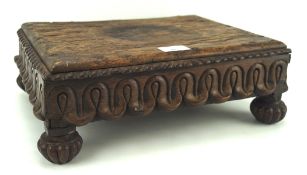 An oak footstool of rectangular form with carved apron and raised on fluted bun supports, L35.