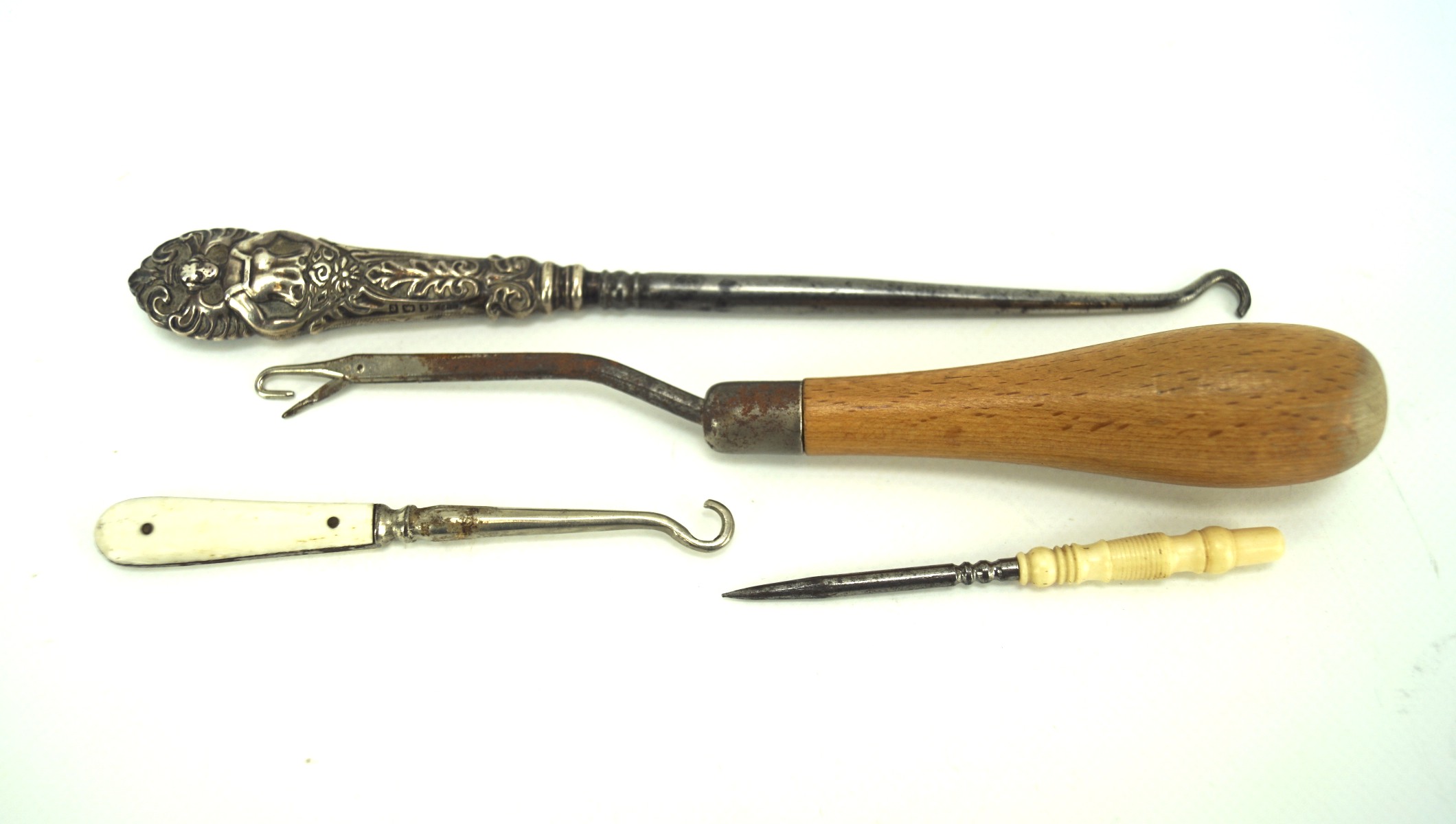 Four button hooks and sewing tools, including a bone handled stiletto, silver handled button hook,