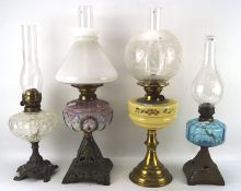 Four oil lamps, each having a glass reservoir and glass funnel, two with original glass shades,