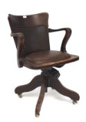 A early 20th century oak framed swivel chair, upholstered in brown faux leather,