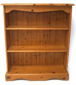 A contemporary pine bookcase, containing two shelves, mounted on a plinth base,