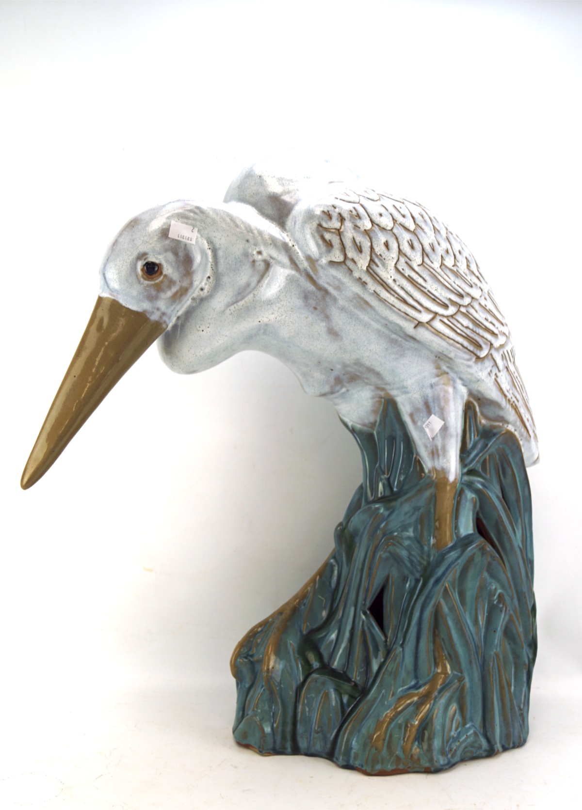 A large glazed ceramic figure of a crane, perched upon some reeds, approx.