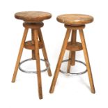 A pair of 20th century wooden swivel stools, with chrome foot rests,
