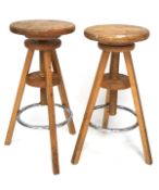 A pair of 20th century wooden swivel stools, with chrome foot rests,