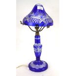 A cut-glass blue stained electric lamp, mounted on a circular base,