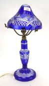 A cut-glass blue stained electric lamp, mounted on a circular base,