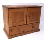 A contemporary pine media cabinet, the two door cupboard raised over a single long drawer,