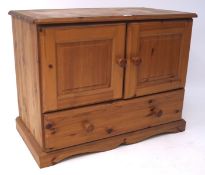 A contemporary pine media cabinet, the two door cupboard raised over a single long drawer,