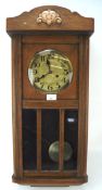 An early 20th century oak case wall clock, the dial with Arabic numerals denoting hours,