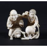 A late 19th century Japanese carved ivory okimono, depiciting a couple with a monkey and an octopus,