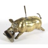 An inkwell or cruet stand cast as a brass pig before a basket spoon or pen-rest, with glass liner,