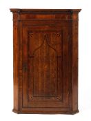 An 18th century inlaid oak wall corner cupboard the paneled door decorated with a central shell