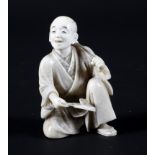 A late 19th century Japanese carved ivory okimono depiciting a seated gentleman taking tea,