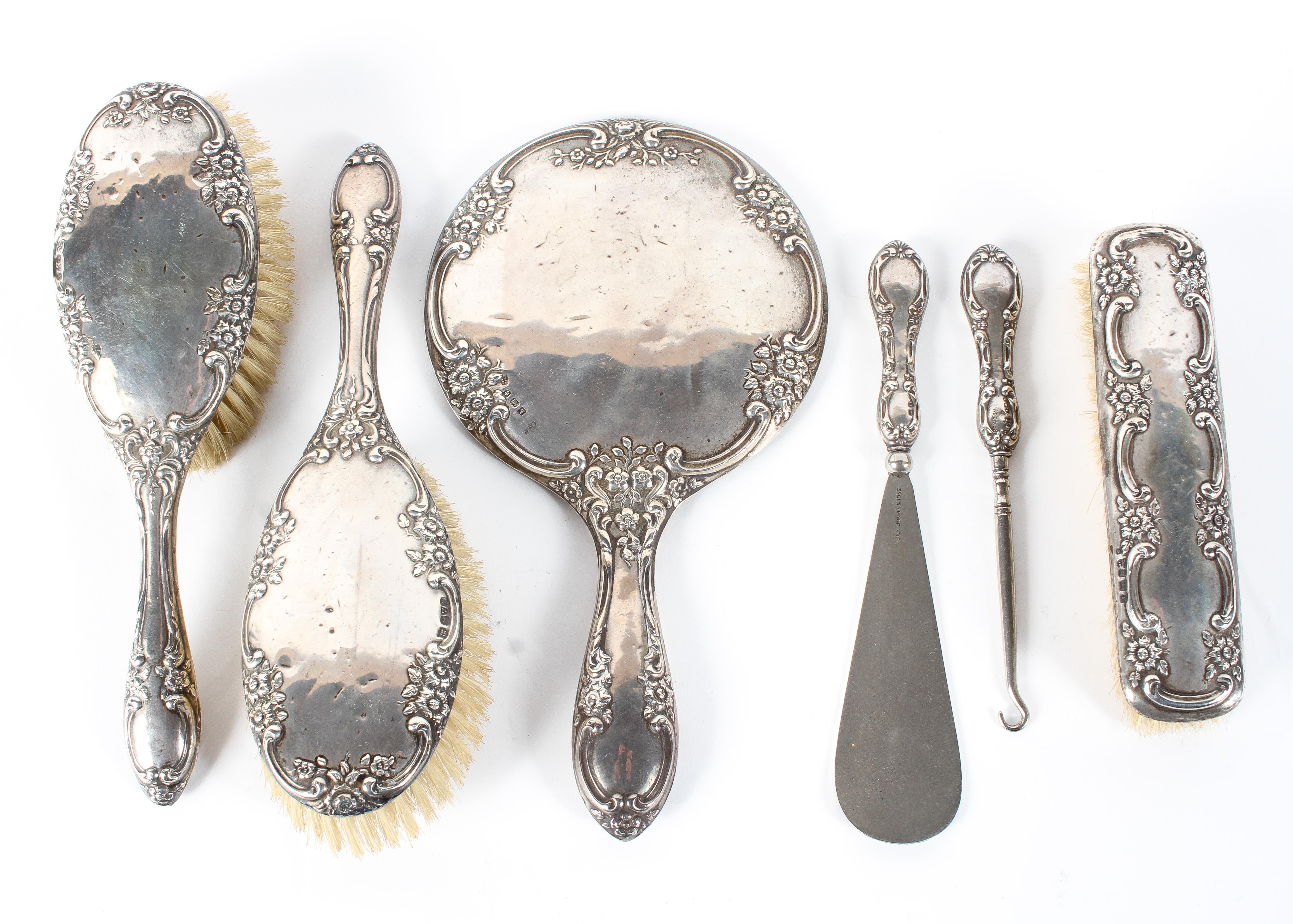 A silver backed four piece dressing table set, including brushes, hand mirror and shoe horn,