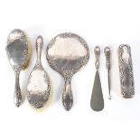 A silver backed four piece dressing table set, including brushes, hand mirror and shoe horn,