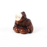 A 19th century wood netsuke of a man in a patterned robe crouching