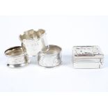 Three assorted silver napkin rings and a silver topped stamp box,