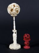 An early 20th century Chinese carved ivory puzzle ball and stand and a stained red ivory puzzle