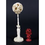 An early 20th century Chinese carved ivory puzzle ball and stand and a stained red ivory puzzle