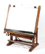 An early 20th century pine adjustable drawing board on stand,