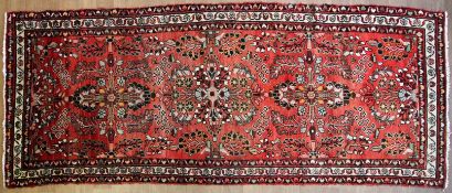 A Hamadan floral red-ground rug, woven with radiating floral medallions in cream, black,