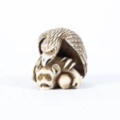 A late 19th/early 20th century ivory netsuke of an eagle catching a frightened monkey, eyes inlaid,