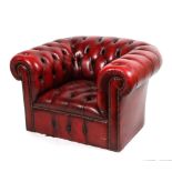 A 20th century red leather chesterfield armchair, with studded scroll armrests and front,