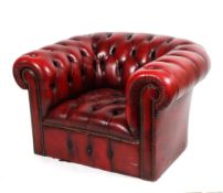 A 20th century red leather chesterfield armchair, with studded scroll armrests and front,