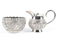 An Indian silver creamer and sugar bowl heavily decorated with Goddesses,