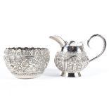 An Indian silver creamer and sugar bowl heavily decorated with Goddesses,