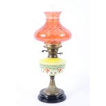 A late 19th century oil lamp with enamelled yellow glass body and cranberry shade,