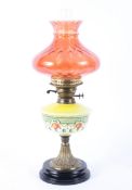 A late 19th century oil lamp with enamelled yellow glass body and cranberry shade,