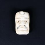 A late 19th/early 20th century ivory mask netsuke of a man,